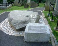 Saint Patrick's Grave:
		INSCRIPTION

[Saint Patrick was born in Britain. At sixteen he was sold into slavery. He escaped to France, but one night in a dream he heard the voice of the Irish calling him back. How Patrick answered that call and brought Christianity to Ireland is one of the most splendid chapters of our history. 

According to tradition the remains of Saint Patrick with those of Saint Brigid and Saint Columba who was also known as Columcille, were reinterred on the site by John de Courcy in the 12th Century thus fulfilling the prophecy that the three saints would be busied in the same place.] 

The large granite boulder was placed in the graveyard of Down Cathedral in 1900 by F.G. Bigger of the Belfast Naturalist Field Club. On the stone is carved the name PATRIC and a cross. It is a memorial, not a tombstone. 

Photo - Pat Devlin